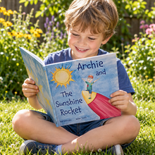 Load image into Gallery viewer, Boy reading a book called Archie & The Sunshine Rocket in a garden setting.