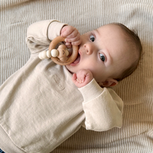 Load image into Gallery viewer, Baby lying on a beige blanket with a wooden teething ring