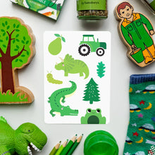 Load image into Gallery viewer, Collection of green-themed items including a card with illustrations, toys, and stationery on a white background.