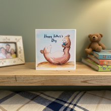 Load image into Gallery viewer, Card with bear illustration and 'Happy Father's Day' text on a shelf with books and a teddy bear.