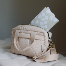 Load image into Gallery viewer, Beige quilted baby bag with a scallop design changing mat on a light surface