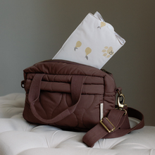 Load image into Gallery viewer, Brown quilted baby bag with pear design changing mat on a light grey surface.