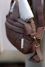 Load image into Gallery viewer, Brown quilted changing bag with gold zipper and brown strap on a blurred background