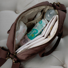 Load image into Gallery viewer, Open brown changing bag with baby items on a white cushioned surface