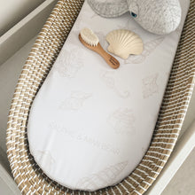 Load image into Gallery viewer, Baby bassinet with seashell mattress cover, plush toy, wooden brush, and seashell in a neutral setting.