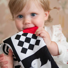 Load image into Gallery viewer, Child holding a black and white sensory square with red corner detail