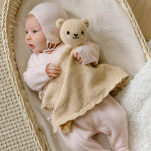 Load image into Gallery viewer, Baby in a pink outfit holding a teddy bear and blanket in a wicker basket.