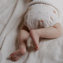 Load image into Gallery viewer, Newborn baby wearing a patterned cloth nappy on a soft fabric surface
