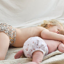 Load image into Gallery viewer, Two children wearing patterned cloth nappies lying on a soft surface.