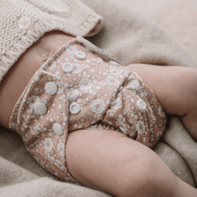 Load image into Gallery viewer, Close-up of a baby wearing a patterned cloth nappy on a beige blanket.