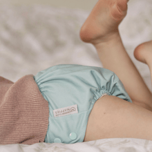 Load image into Gallery viewer, Mint green cloth nappy worn by a child on a soft surface