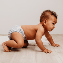 Load image into Gallery viewer, Baby in a cloth nappy crawling on a wooden floor with a neutral background