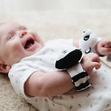 Load image into Gallery viewer, Baby wearing a black and white striped wrist rattles on a neutral background
