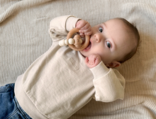 Load image into Gallery viewer, Baby lying on a beige blanket with a wooden teething ring

