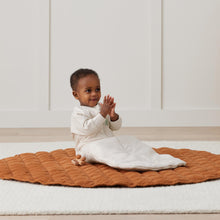 Load image into Gallery viewer, Child sitting on a textured orange blanket in a minimalistic room.
