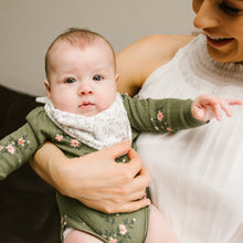 Load image into Gallery viewer, Baby wearing a greenery bandana bib in a green outfit with floral patterns held by a woman.
