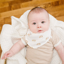 Load image into Gallery viewer, Baby wearing a striped outfit and bib with rainbow design laid in moses basket.
