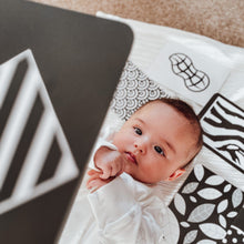 Load image into Gallery viewer, Newborn baby lying on a patterned blanket with a flashcard in the foreground.
