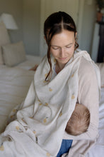 Load image into Gallery viewer, Woman holding a baby covered in a pear design muslin in a bedroom setting.
