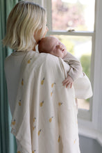 Load image into Gallery viewer, Woman holding a baby with pear design muslin over her shoulder, standing by a window.
