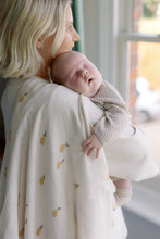 Load image into Gallery viewer, Woman holding a baby wrapped in a blanket with pear pattern, looking out of a window.
