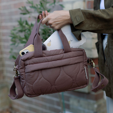 Load image into Gallery viewer, Person holding a brown quilted changing bag with a blurred background
