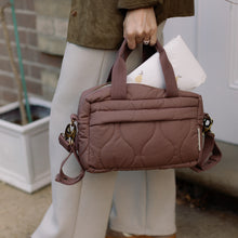 Load image into Gallery viewer, Person holding a brown quilted changing bag with a neutral background
