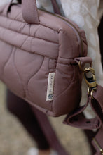 Load image into Gallery viewer, Close-up of a quilted changing bag with Ralphie Bear label on a blurred background
