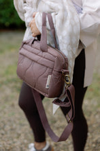 Load image into Gallery viewer, Person holding a quilted brown changing bag with a blurred background
