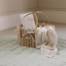 Load image into Gallery viewer, Wicker basket with pear design muslin and travel changing mat on a quilted mat against a neutral wall.
