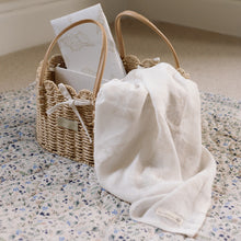 Load image into Gallery viewer, Wicker basket with seashell design muslin and travel changing mat on a Ralphie Bear wildflower playmat.
