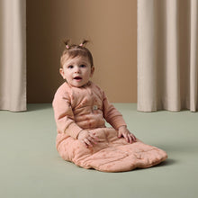 Load image into Gallery viewer, Baby in a pink Ergo Pouch sitting on a green floor with beige curtains in the background
