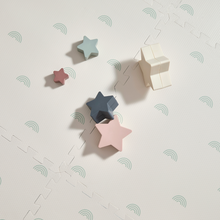 Load image into Gallery viewer, Colourful star-shaped wooden blocks on a cream background with subtle sage rainbow patterns.
