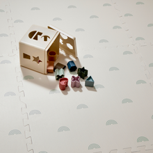 Load image into Gallery viewer, Wooden shape sorting cube with colourful blocks on a cream with sage rainbow pattern playmat.
