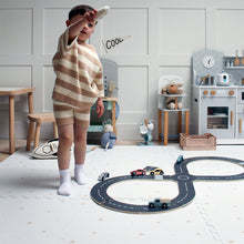 Load image into Gallery viewer, Child playing with toy cars on a road mat in a playroom.
