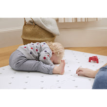 Load image into Gallery viewer, Child playing on a mat with a red toy, surrounded by a basket and wooden floor.
