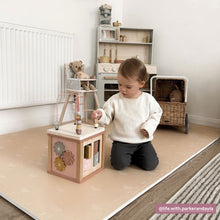 Load image into Gallery viewer, Child playing with a wooden toy in a playroom with toys and furniture.
