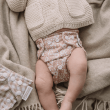 Load image into Gallery viewer, Baby wearing a patterned cloth nappy with a beige knit cardigan on a soft, textured blanket.
