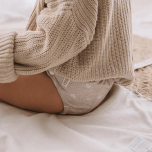 Load image into Gallery viewer, Toddler wearing a beige knitted jumper with a patterned beige cloth nappy on a soft surface
