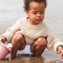 Load image into Gallery viewer, Child playing with a pink bucket wearing a cloth nappy in water
