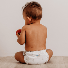 Load image into Gallery viewer, Baby sitting on a wooden floor wearing a white cloth nappy in George Pig design, holding a red apple

